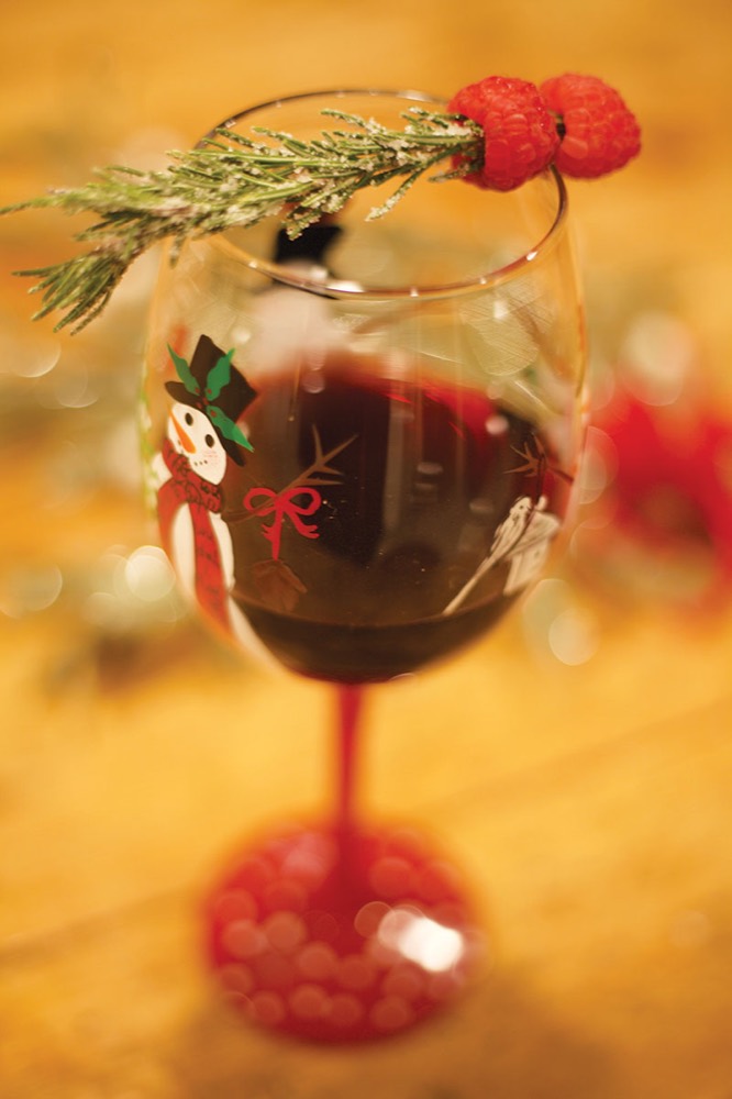 Wine glass with a frosted rosemary and raspberry garnish