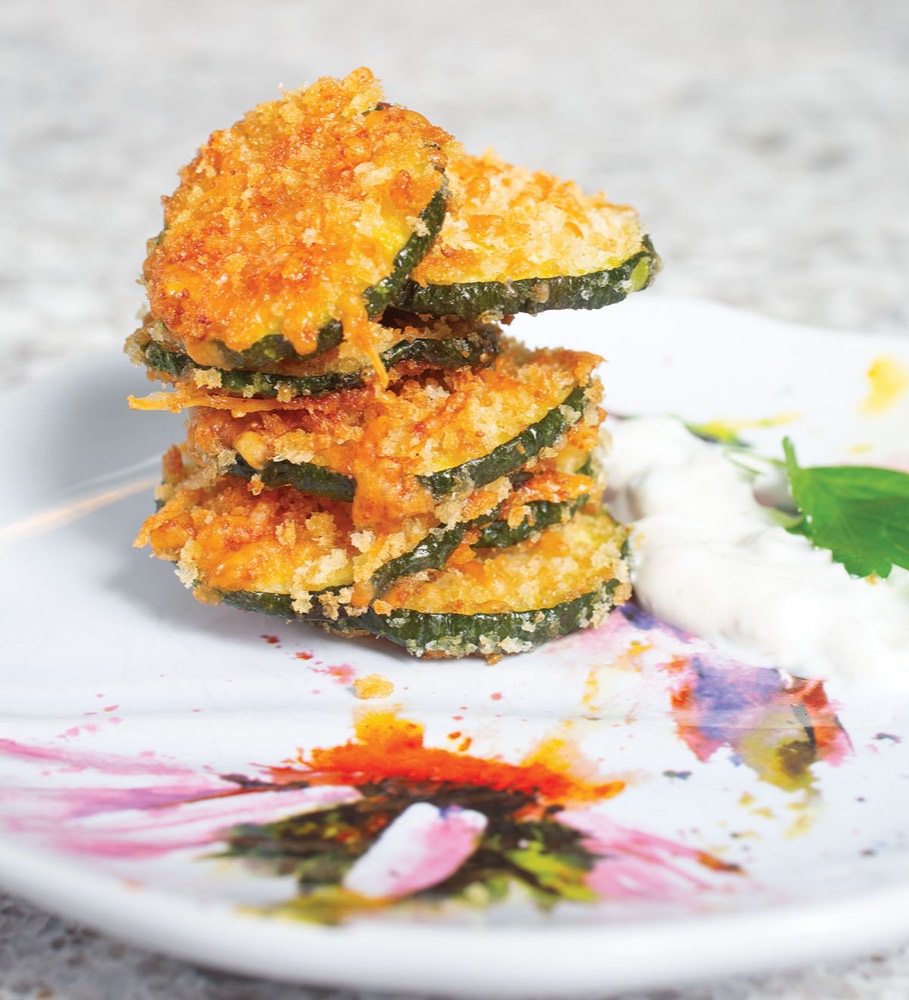 Stack of zucchini parmesan crisps with herb garnish